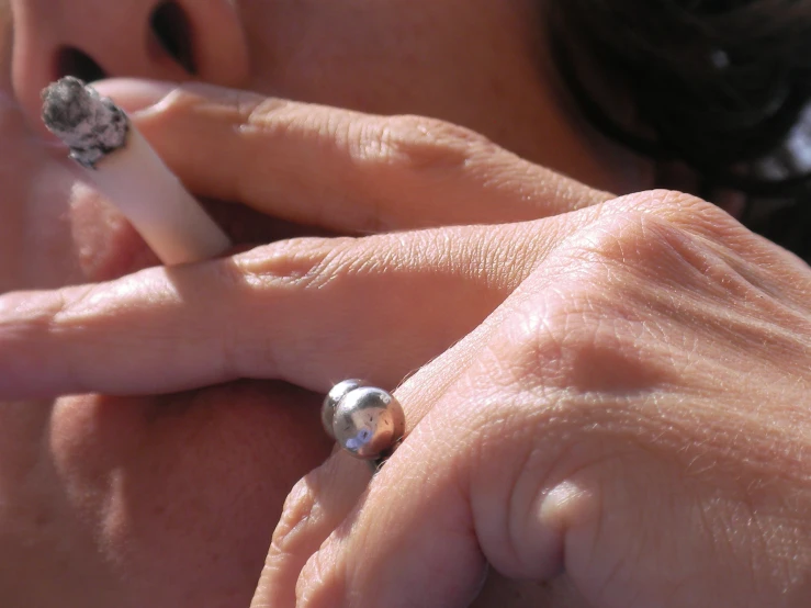 an older lady holding a cigarette next to her face