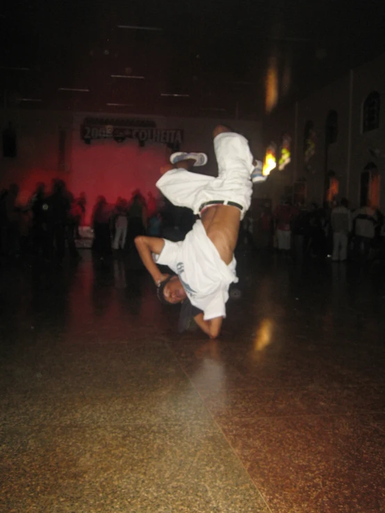a man doing a handstand on his legs in the middle of a dance floor