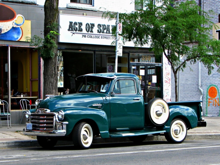 a green truck is parked next to a store