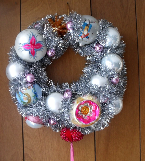 an ornament wreath with shiny tinsel is on the floor