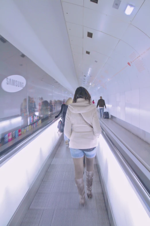 an older woman is pulling luggage down an escalator