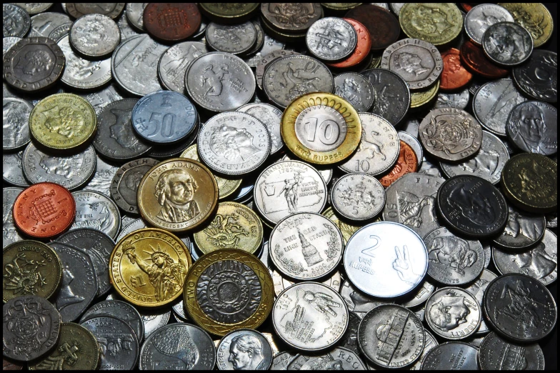 two coins and one dime sitting on a bunch of other coins