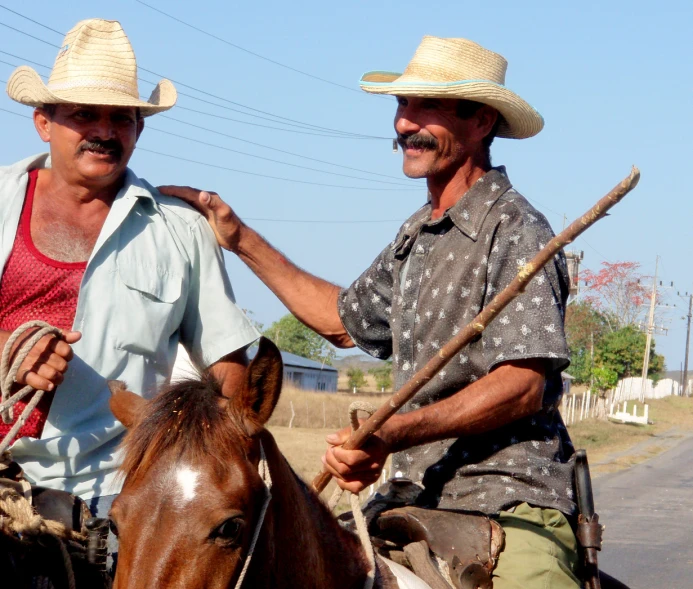 two men in hats sitting on top of horses