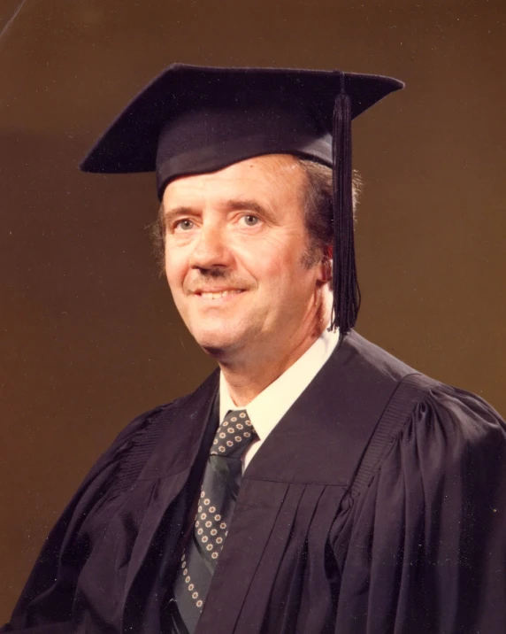 a man with a black graduation cap and tie posing for a po