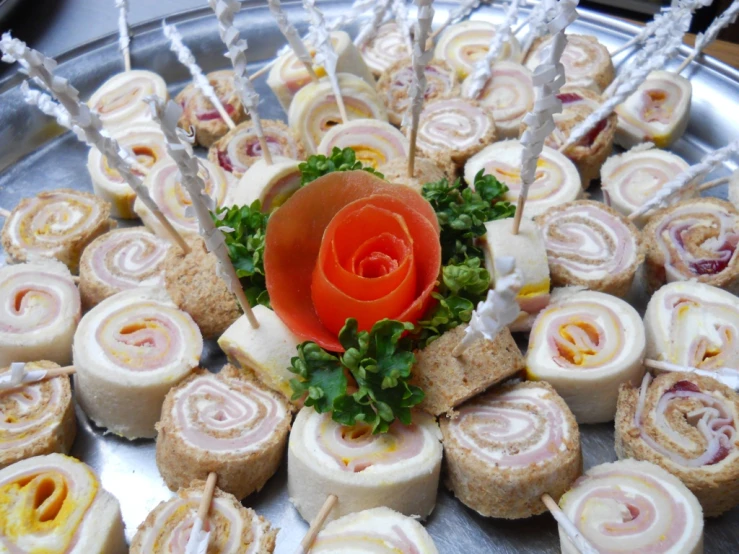 rolls with orange flower are arranged on a silver platter