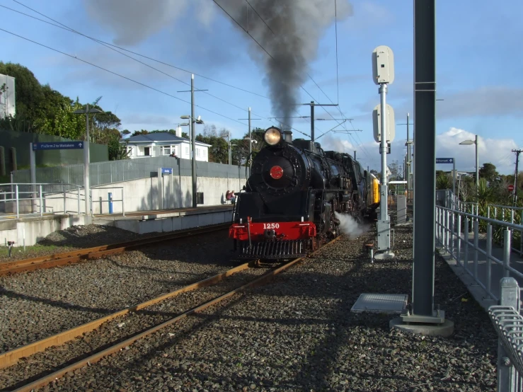 train traveling past a train station with steam coming out