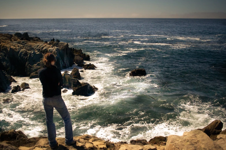 man standing near the water looking at the ocean