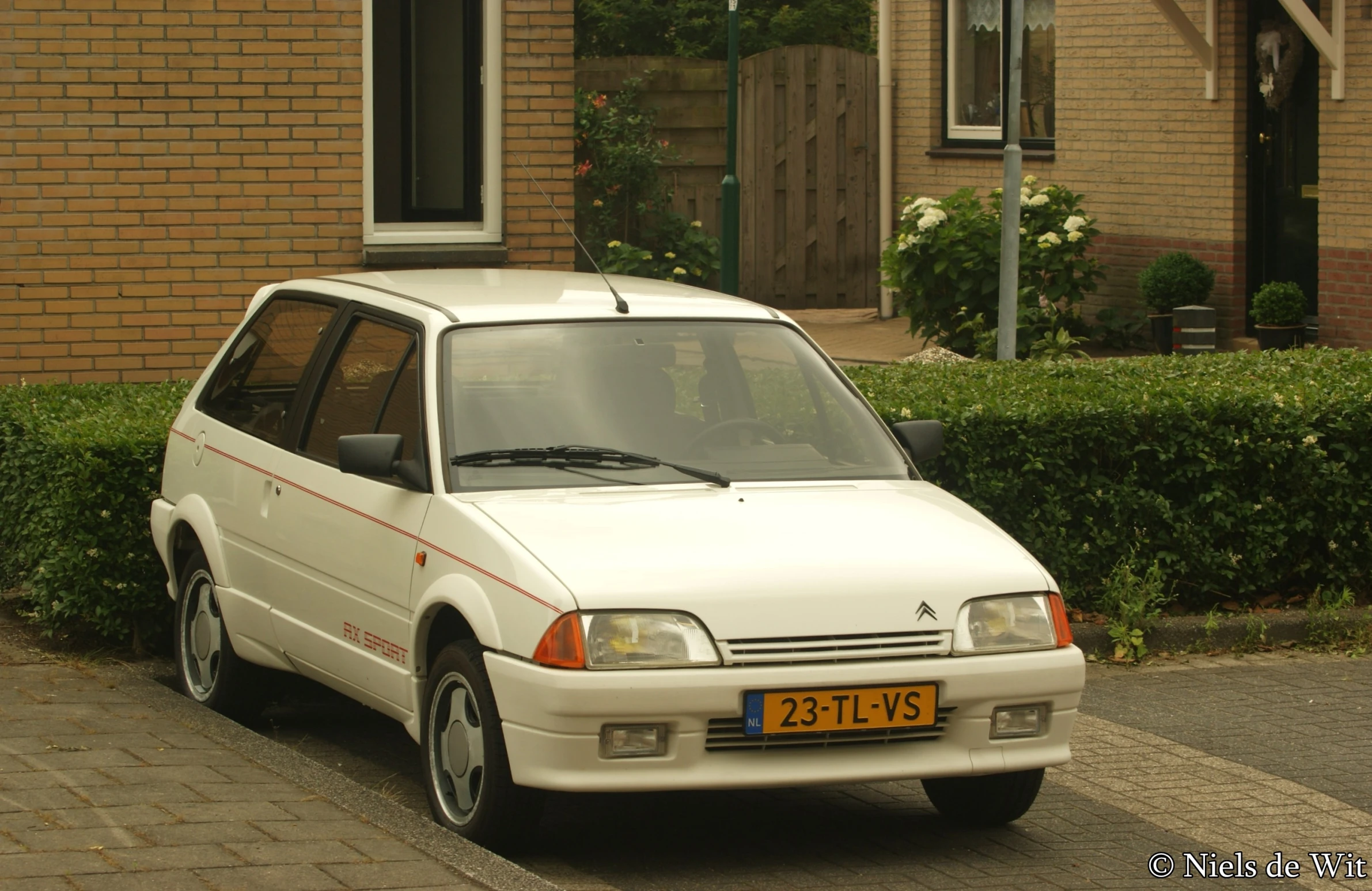 an orange and white car parked in front of a brick building