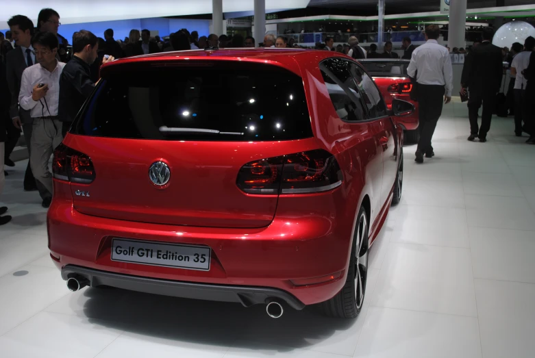 a red volkswagen car parked on display at an auto show