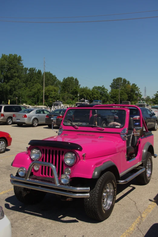 a pink jeep with the door open in a parking lot