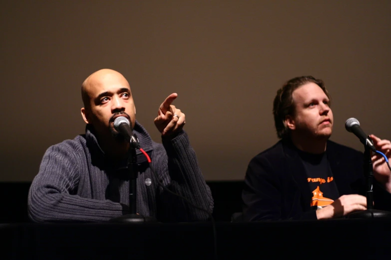 two people in a lecture hall one has his fingers raised up