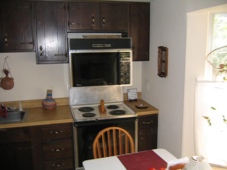 a stove that has wooden cabinets and wood chairs