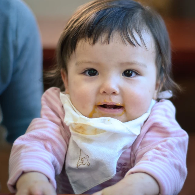 a little girl sitting in her high chair eating