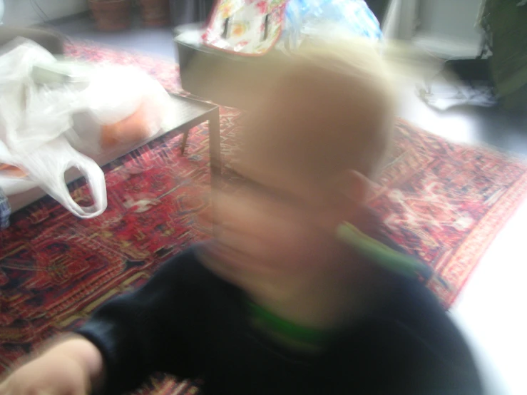 blurry po of a toddler standing in front of a living room with a wii remote