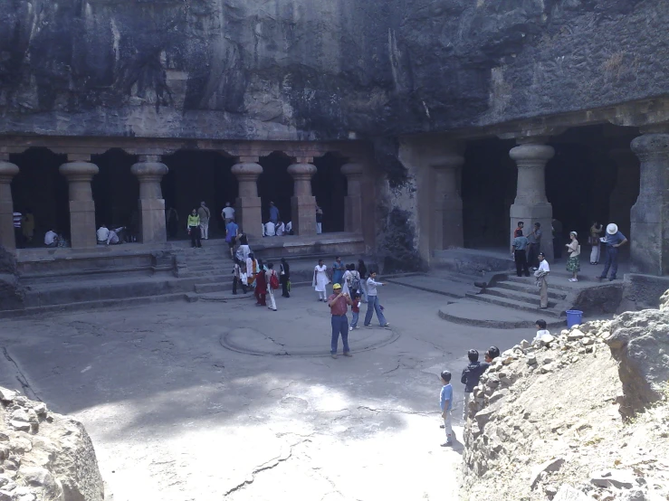 a group of people walk around a very large rock structure