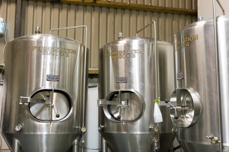 two stainless steel vessels are lined up beside one another