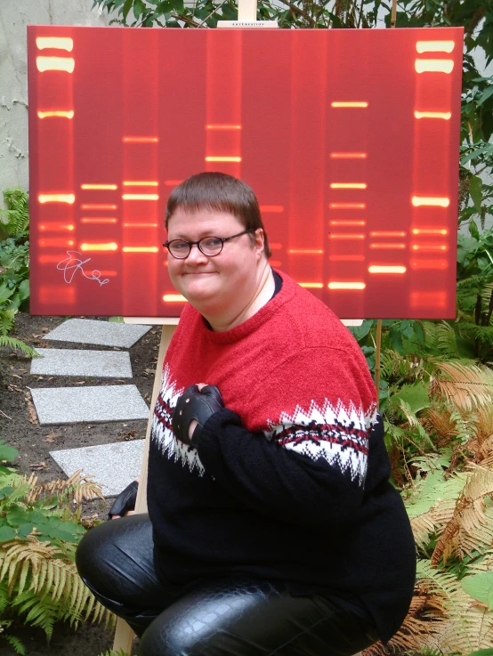 a woman in a sweater, holding her dog near an electronic screen