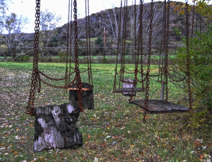 there are many swings that are outside in the grass