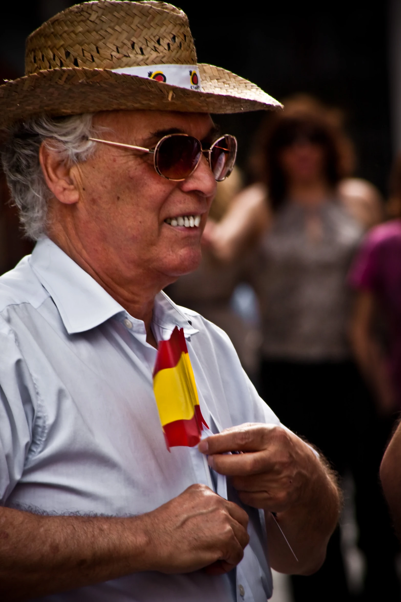 a man with a sombrero and sunglasses on his head, has a red, white and yellow tie around his neck