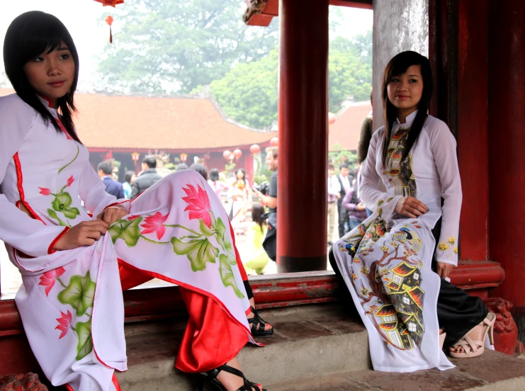 two woman are sitting and standing outside near one another