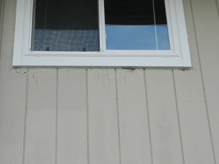 a window with a blue curtain sits open on the wall of a building