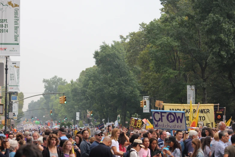 a large crowd of people stand in a street with a sign on the side