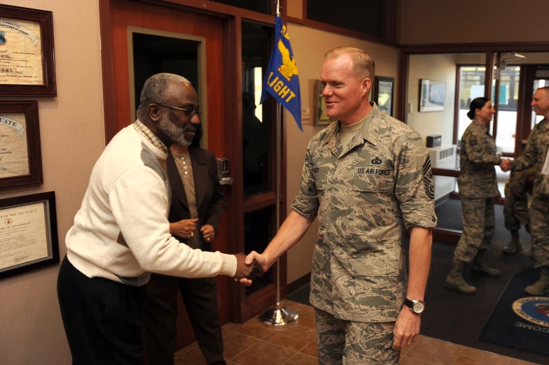 a man in uniform is shaking another man's hand