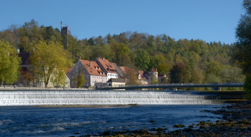 water rushing over a river with houses in the background