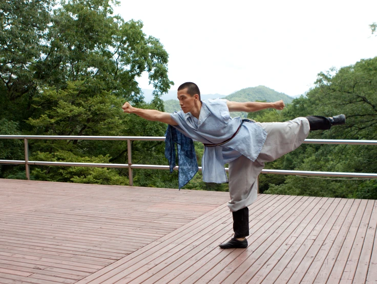 a man does a standing yoga position near a railing