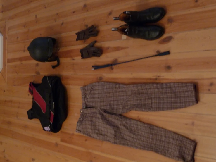 a pair of shoes, a helmet and some other accessories are scattered on a hardwood floor