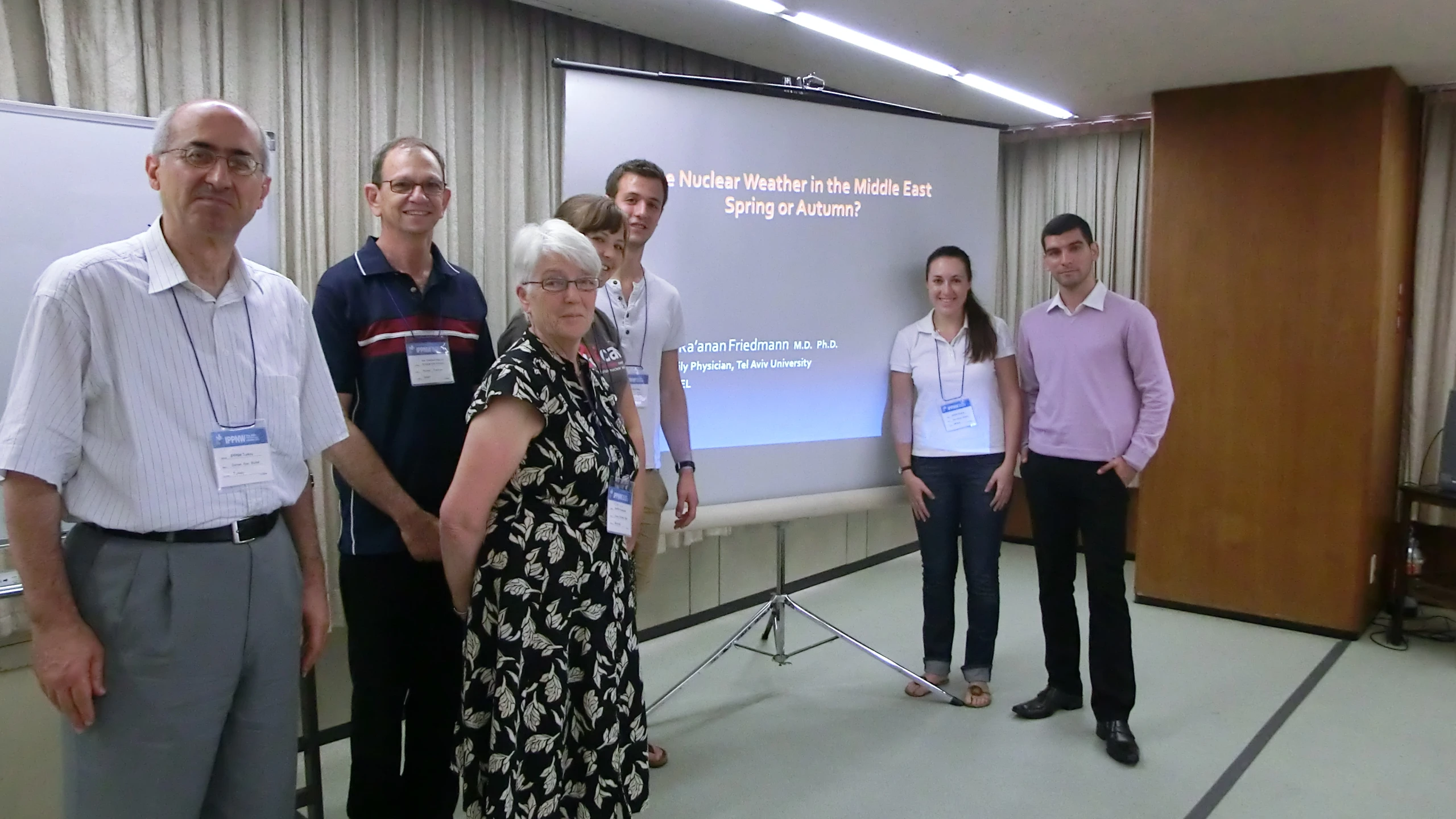 several people stand in front of a presentation screen with a screen showing information on it