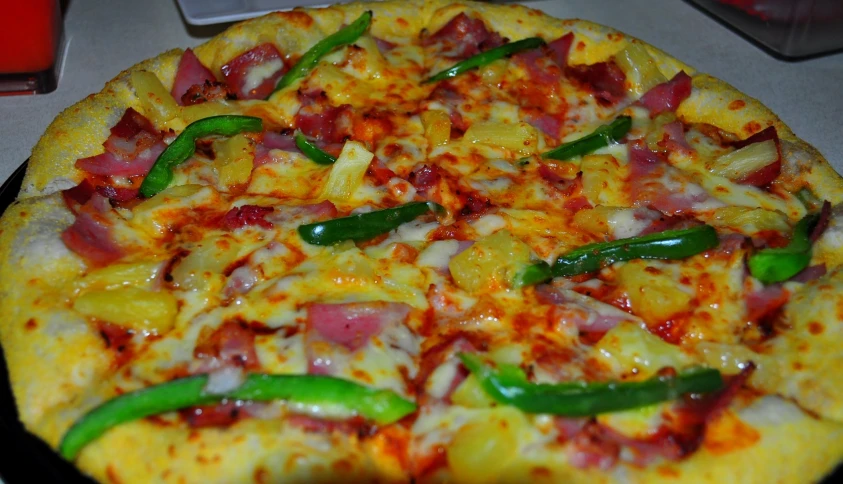 a cooked pizza has peppers and ham on it