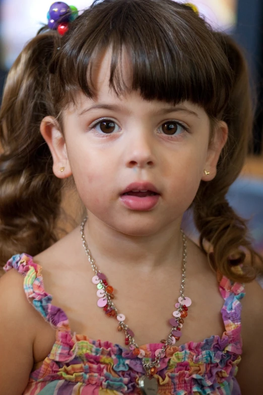 little girl with a colorful dress has a big necklace on her neck