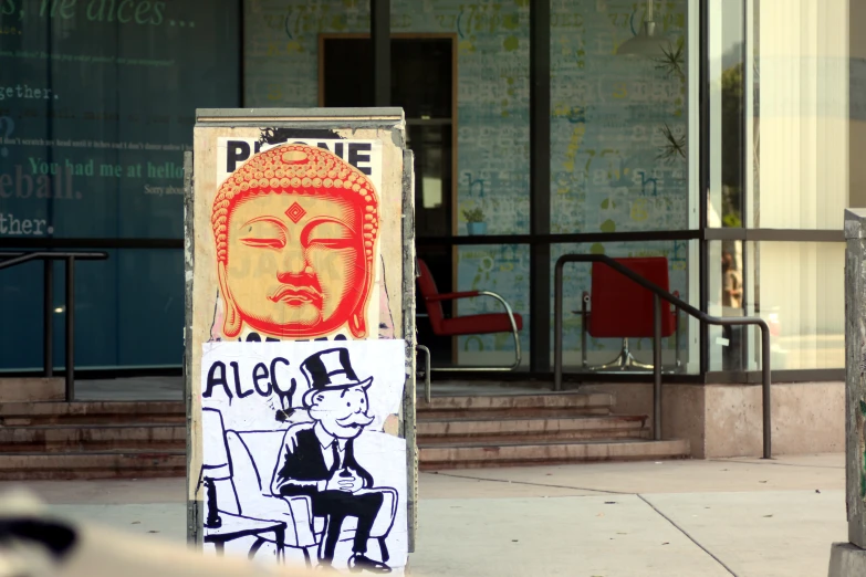 an advertit with a buddha face and other stickers on it