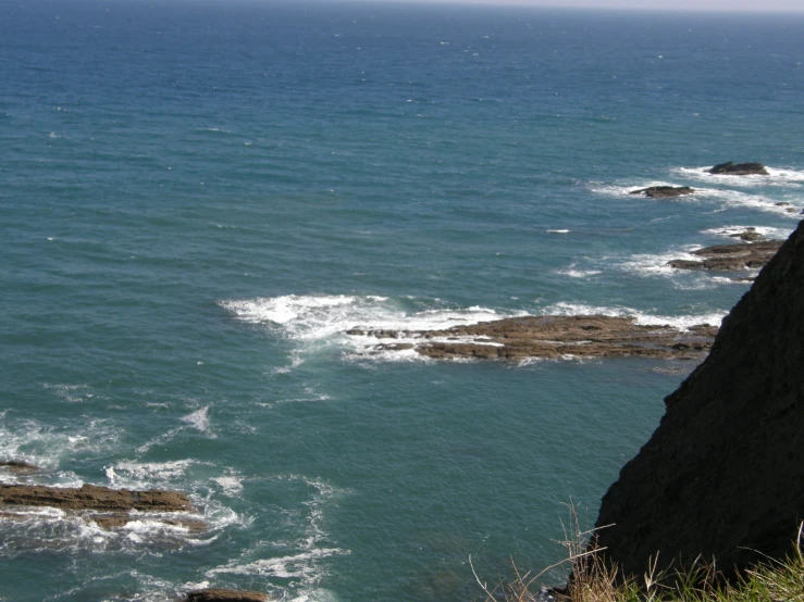 a sea cliff on the shore with waves coming in