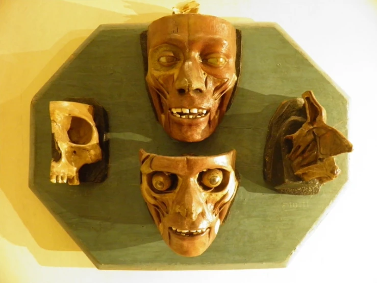 three masks and a skull on a wall