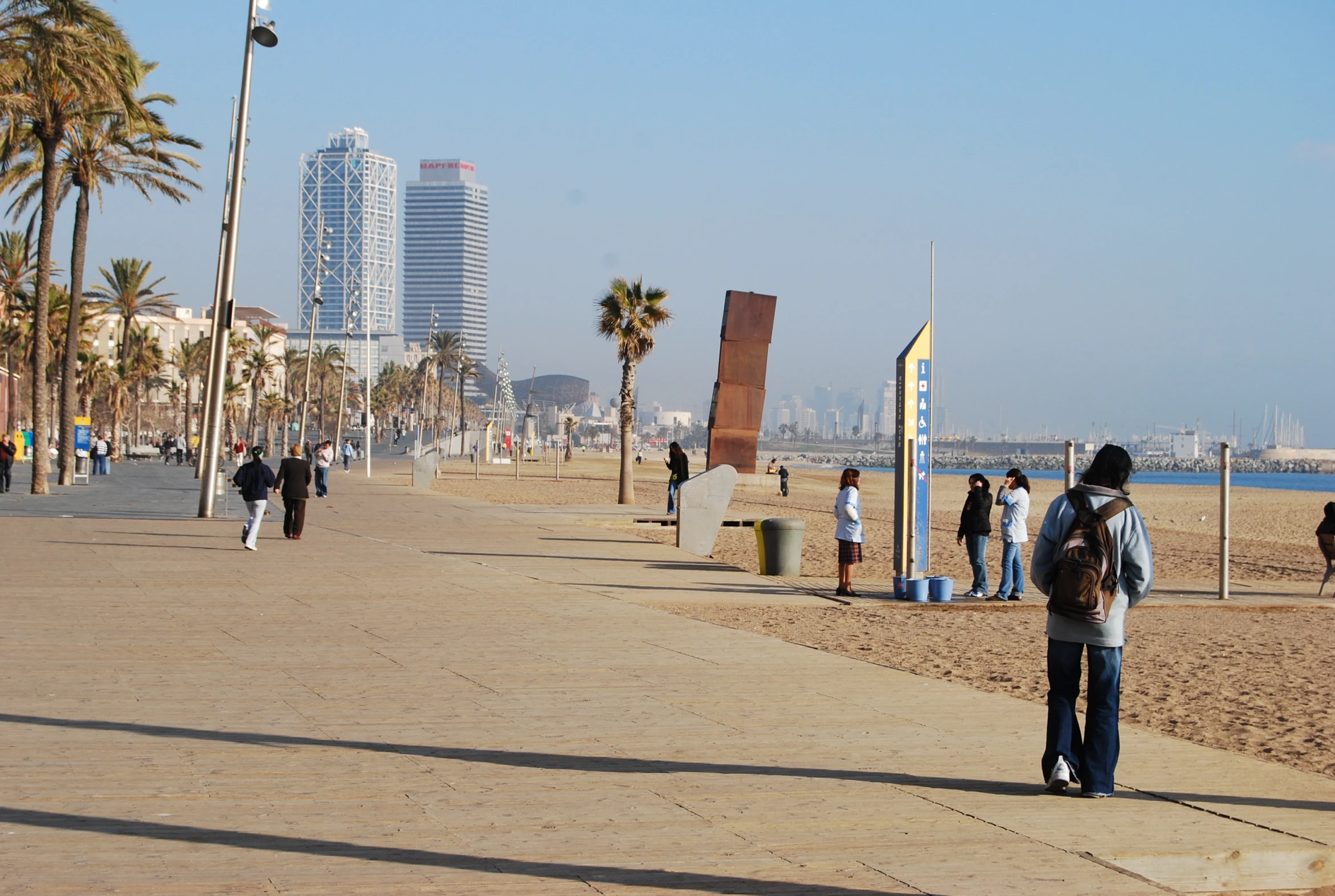 people walking along the beach with tall buildings in the background