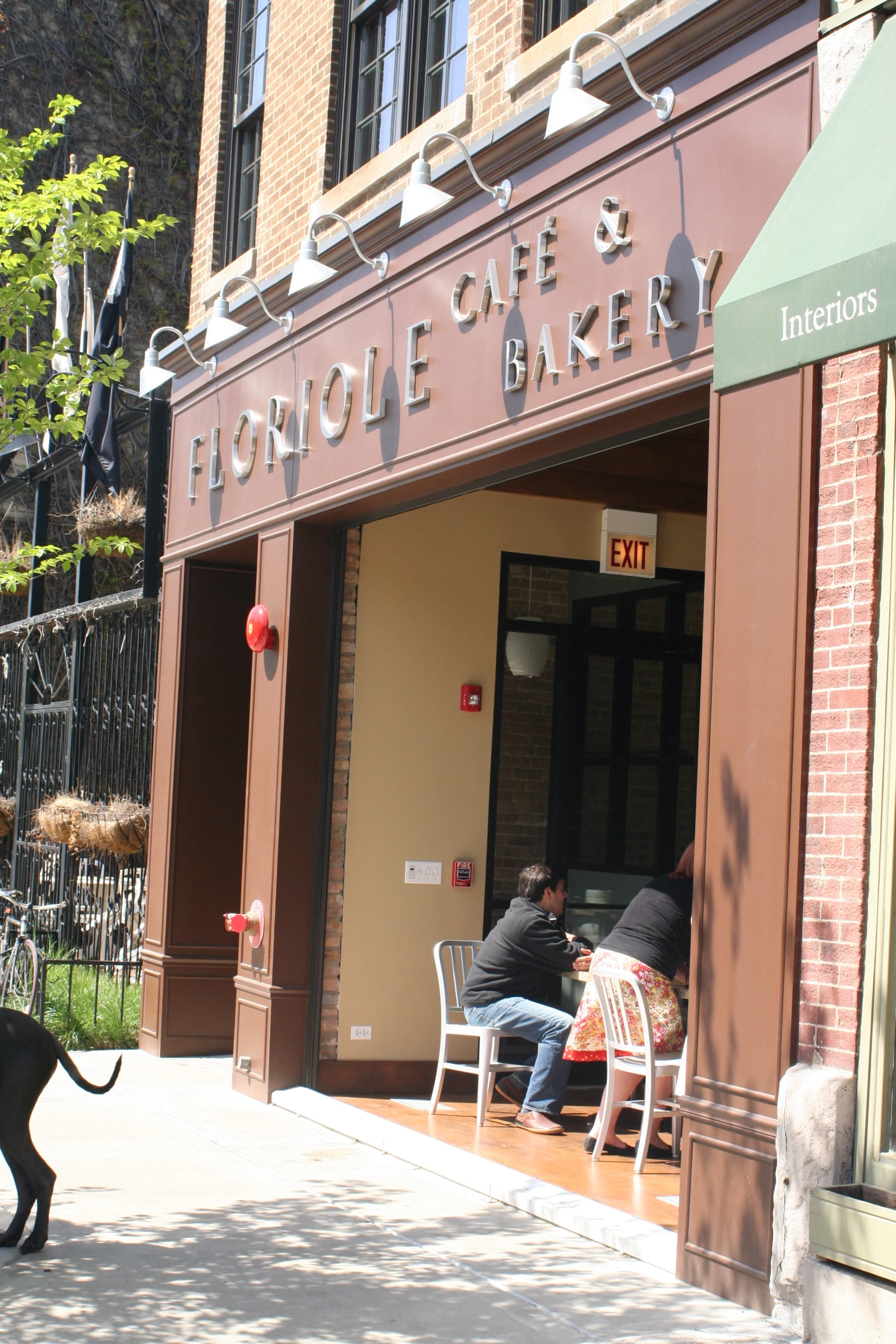 a couple of men sitting down at a table on the sidewalk