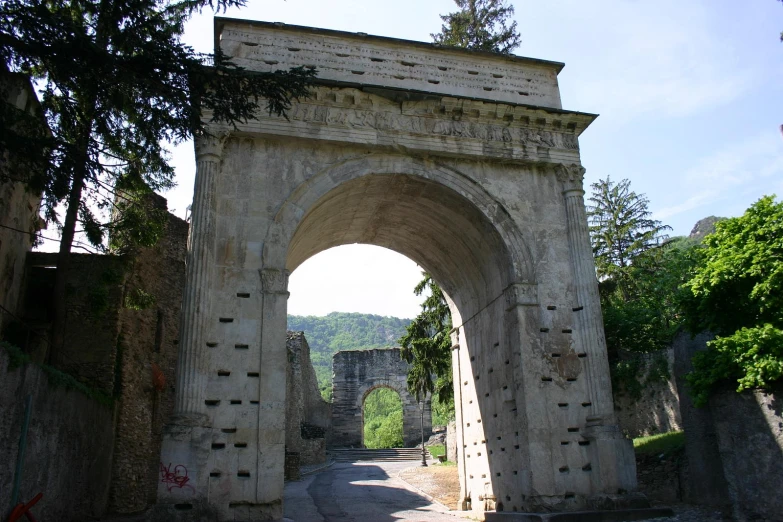 an archway made of cement surrounded by trees