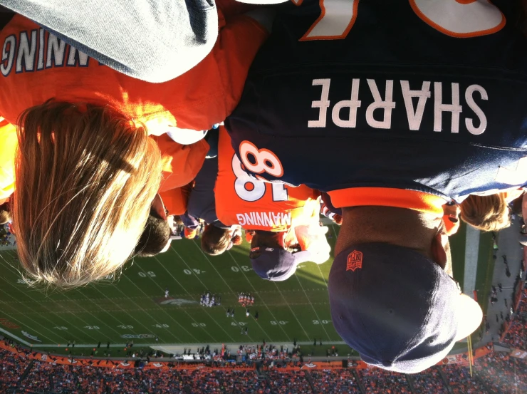 two people with orange shirts watching an orange and blue football game