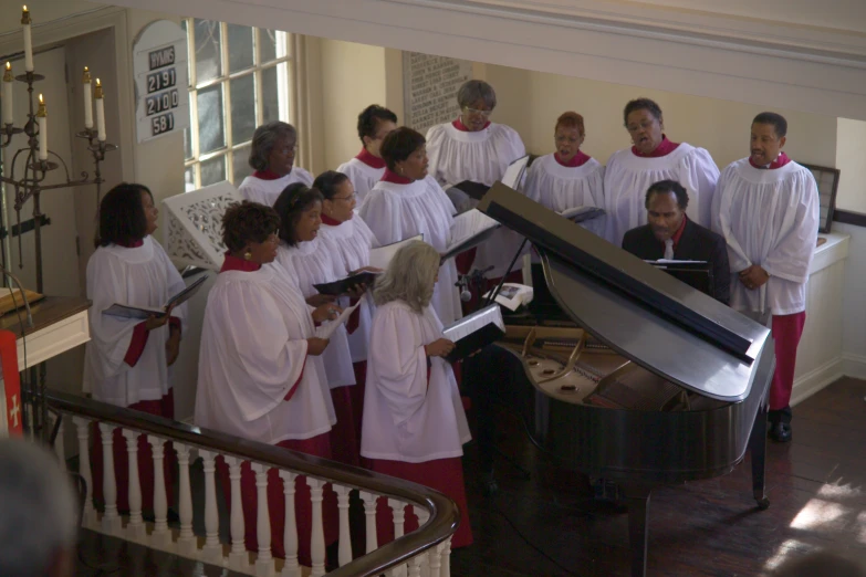 a group of young women dressed in white standing around a piano