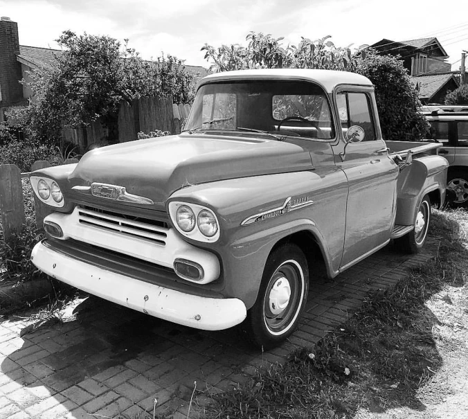 an old black and white truck parked in the front yard