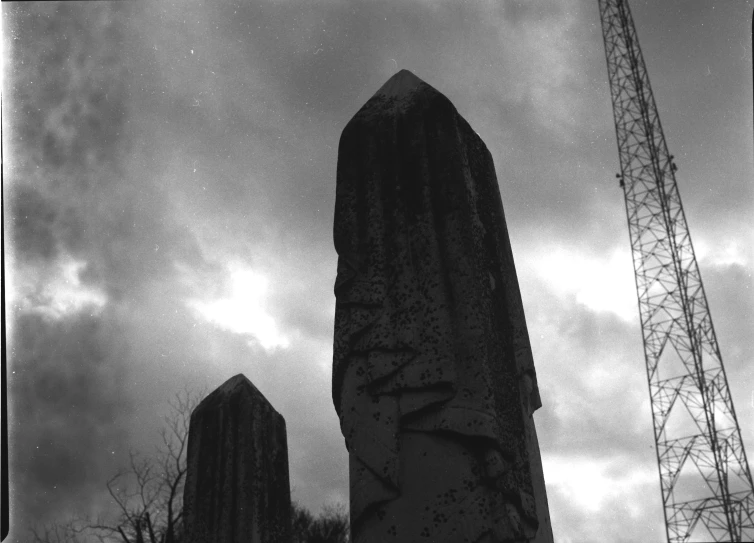 several construction cranes behind a statue near an antenna