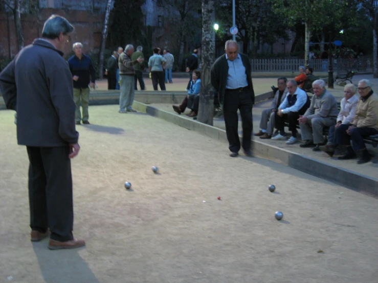 an older man with a suit on looks at a ball on the ground