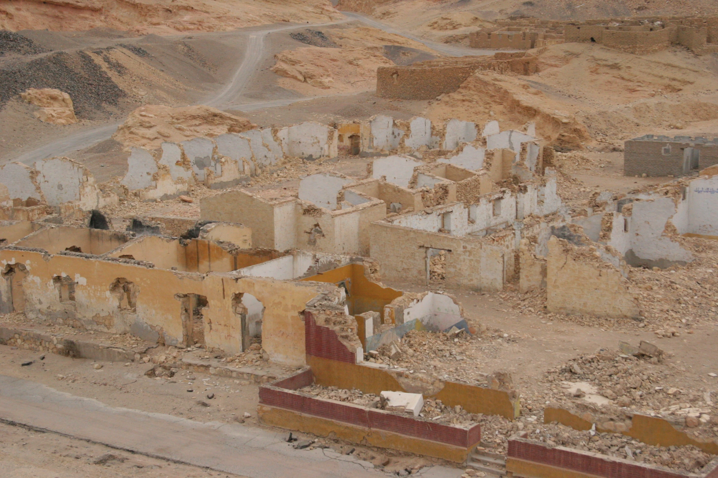 an abandoned building and car in desert terrain