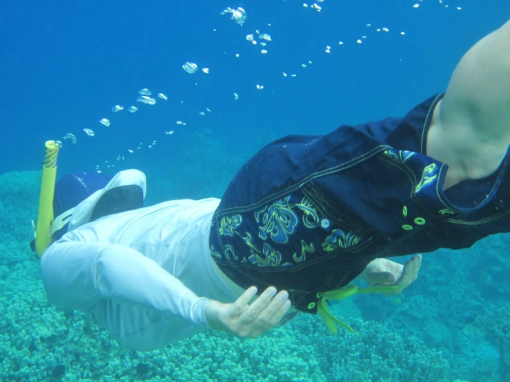 a man in white shorts and a vest snoraks under water