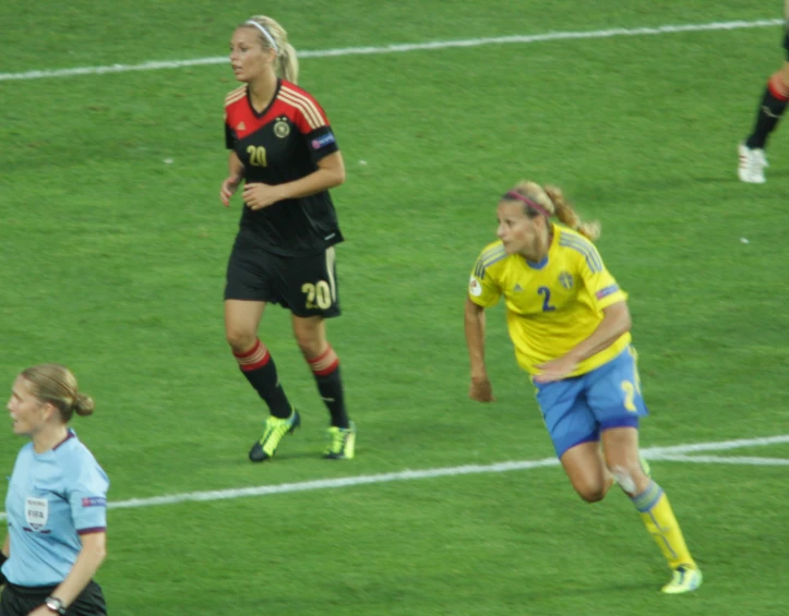 two soccer players run after the ball in a game