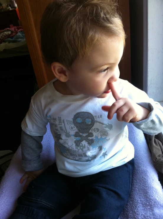 a toddler sitting on top of a towel making the middle finger sign