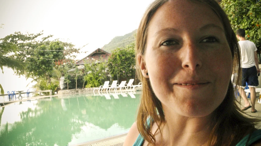 a woman looking into the camera while standing in front of a pool