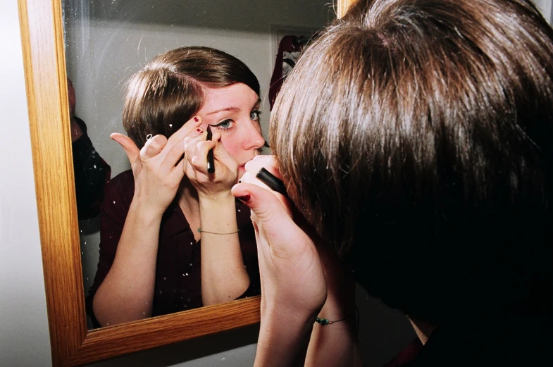 a lady looking at herself in the mirror with a cell phone